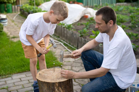 A cute boy in a white T-shirt holds the firewood that dad gives.の写真素材