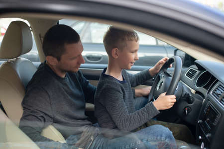 Driving instructor, driving school, child driving, dad and son, long trip, hold the steering wheel, car device, family dayの写真素材