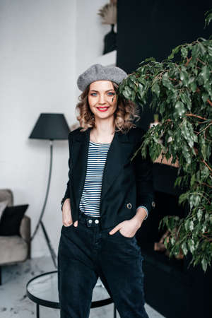 A girl in a beret and red shoes is sitting on a table in the interiorの写真素材