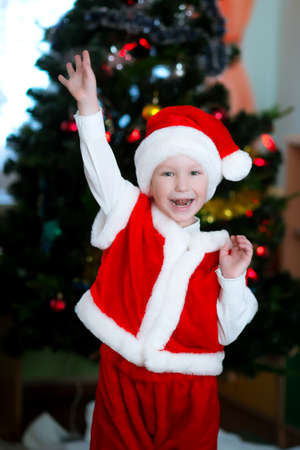 A happy child in a Santa Claus costume raised his handの写真素材