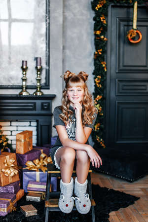 a child with long hair sits near a Christmas tree decorated with balloonsの写真素材