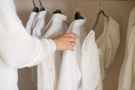 To fix with your hand white things in the closet on a hangerの写真素材