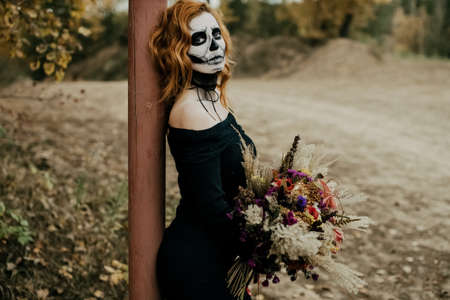 Skull makeup on the girl's face. A girl with a gloomy bouquet for Halloweenの写真素材