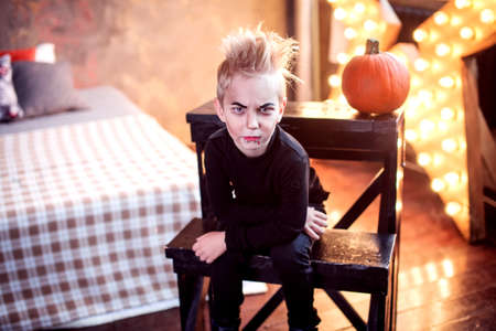 Portrait of a funny little boy in a skeleton costume holding a black balloon. Happy Halloween!