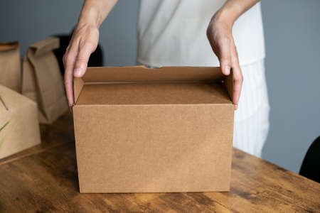 A set of craft boxes and packages on a wooden table with human handsの写真素材