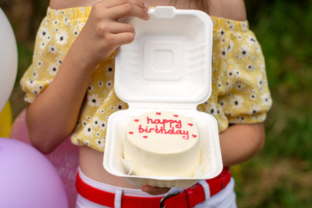 An open box with a bento cake for a birthday in the hands of a person.の写真素材