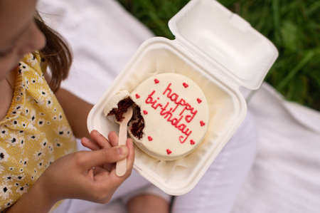 Cute baby breaks a chocolate birthday bento cake with a wooden spoon.の写真素材