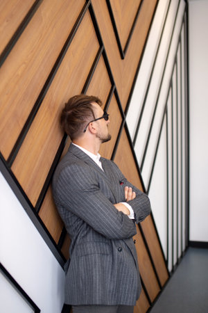 a young man in a suit and sunglasses is standing near the wall with his hands foldedの写真素材