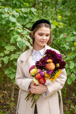 A cute girl with a black headband and long hair holds a bouquet of autumn flowersの写真素材