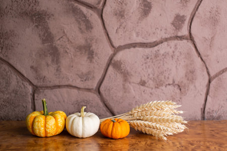 Small festive pumpkins are lying on the table with a bouquet of yellow earsの写真素材