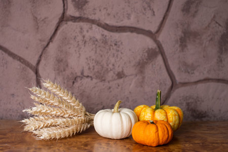 Small festive pumpkins are lying on the table with a bouquet of yellow earsの写真素材