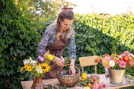 A florist girl collects a bouquet of autumn flowers in a basket on the streetの写真素材