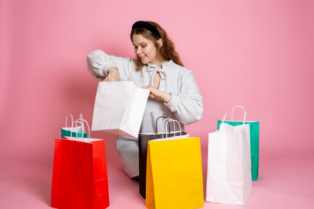 A cute girl holds a paper bag and takes out a purchase from itの写真素材