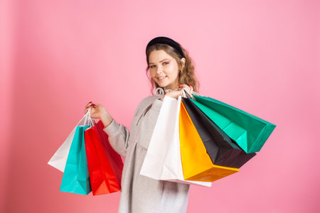 A cute girl is standing with paper bags of different colorsの写真素材