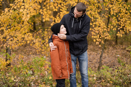 Dad hugs his son and adjusts his hat on the streetの写真素材