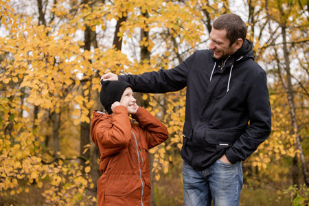 Dad plays with his son in warm clothes in the autumn forestの写真素材