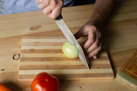 Men's hands cut onions with gozh on a wooden boardの写真素材
