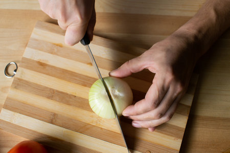 Men's hands cut onions with gozh on a wooden boardの写真素材