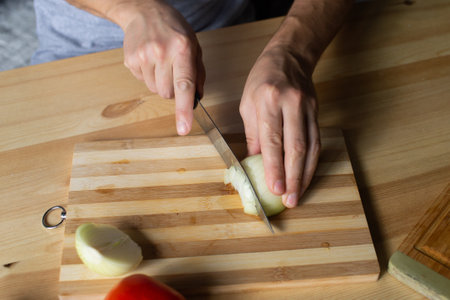 Men's hands cut onions with gozh on a wooden boardの写真素材