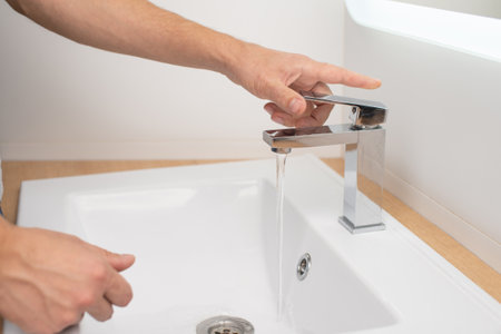 Men's hands turn on the water in the tapの写真素材