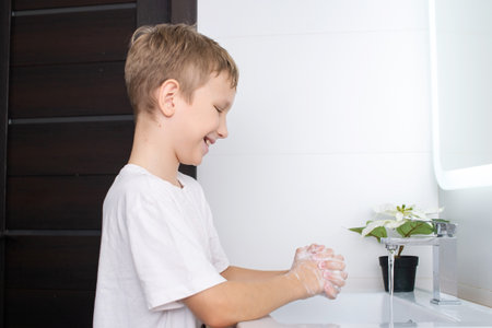 Cute boy lathered his hands and smiling in the bathroomの写真素材
