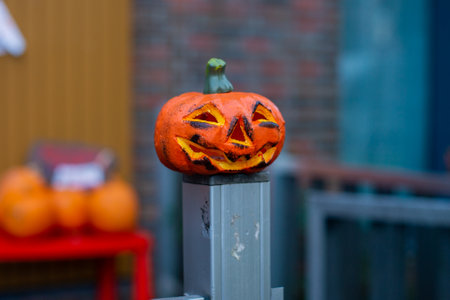 A carved little pumpkin for Halloween stands on the fenceの写真素材