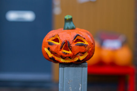 A carved little pumpkin for Halloween stands on the fenceの写真素材