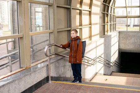 A boy comes out of an underground glass passage with a backpackの写真素材