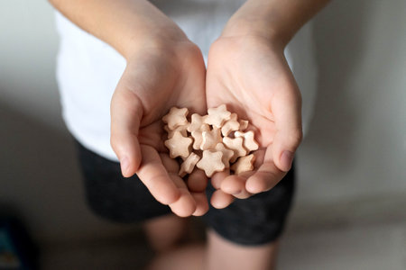 In the hands of a child, a pink vitamin in the shape of an asteriskの写真素材