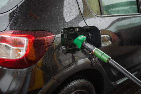 An open tank with a fuel hose at a gas station in a black carの写真素材