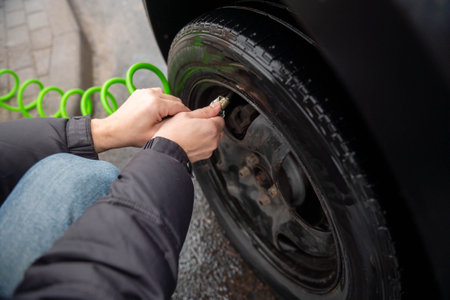 Men's hands hold a pump for a car tireの写真素材