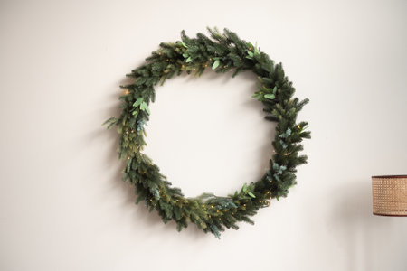 A Christmas wreath made of fir branches is hanging on the wallの写真素材
