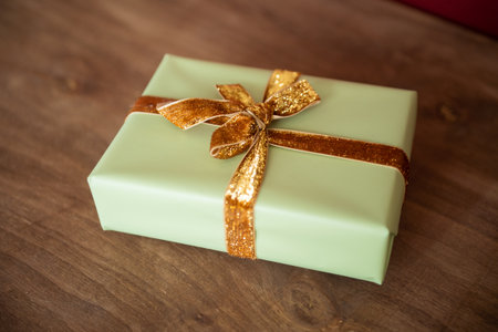 A gift box with a fabric ribbon lies on a wooden tableの写真素材