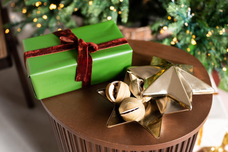 A green box with a gift stands against the background of a Christmas treeの写真素材