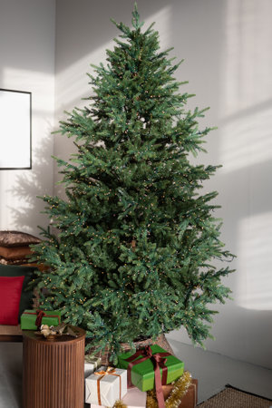 Gift boxes under the Christmas tree with a garland in the interiorの写真素材
