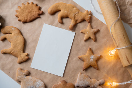 A frame with a white sheet of ginger cookies of different shapes on parchment, a rolling pin on the table and garlandsの写真素材
