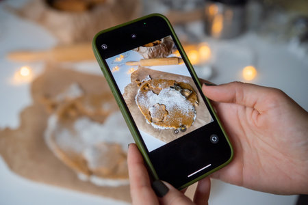 Hands with a phone take pictures of gingerbread dough with moldsの写真素材