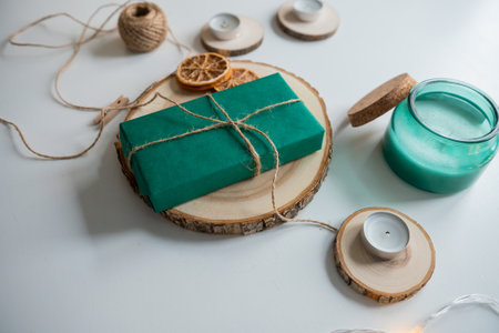 New Year's gift green box on a wooden stand with decor and candlesの写真素材