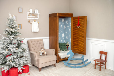 A cozy children's room decorated for Christmas with a decorated Christmas tree and a chair with toysの写真素材