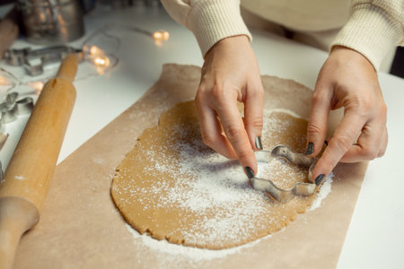 Hands make star-shaped cookies from dough on baking paperの写真素材