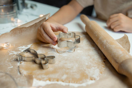 The child's hands make cookies from dough with a mold, the rolling pin lies near the dough with flourの写真素材