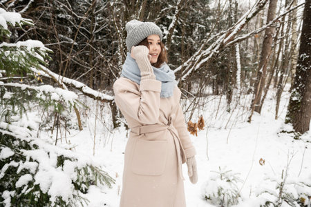 Cute girl in mittens and a hat making a phone call on the street in winterの写真素材