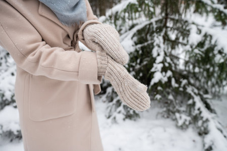 A girl puts on knitted mittens on the street in winterの写真素材