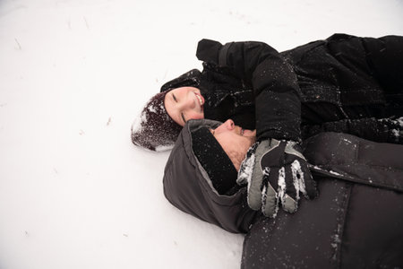Cute boy hugs dad lying in the snow and smilesの写真素材