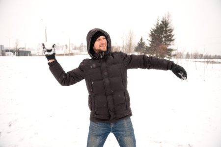A man plays snowballs and smiles, throws snowの写真素材