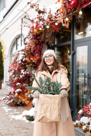 A stylish girl in a hat and coat is happy to buy a Christmas nobilis in the cityの写真素材