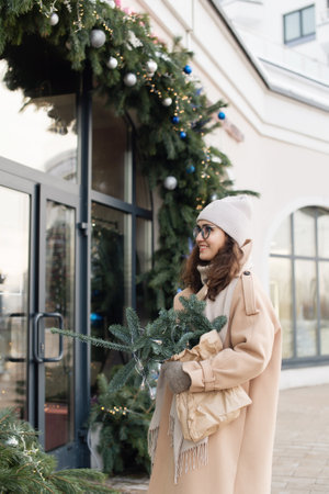 Stylish young woman with nobilis in the city looks into the windows of Christmas shops in winterの写真素材