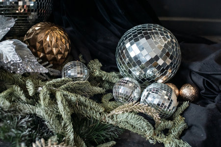 A disco ball of different sizes lies in the branches of nobilis on a black clothの写真素材