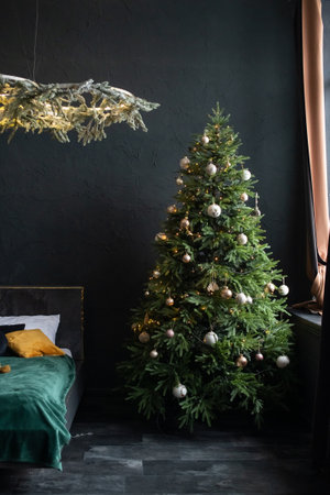 Christmas tree decor with golden toys near the bed in the interiorの写真素材