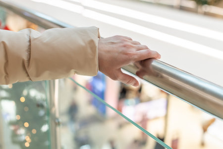 Hand touching a metal handrail in a shopping centerの写真素材